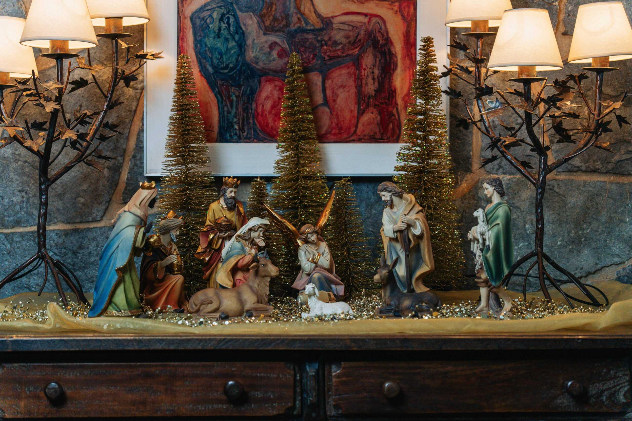 Festive Christmas nativity scene with figurines and warm lighting indoors creating a cozy holiday atmosphere.