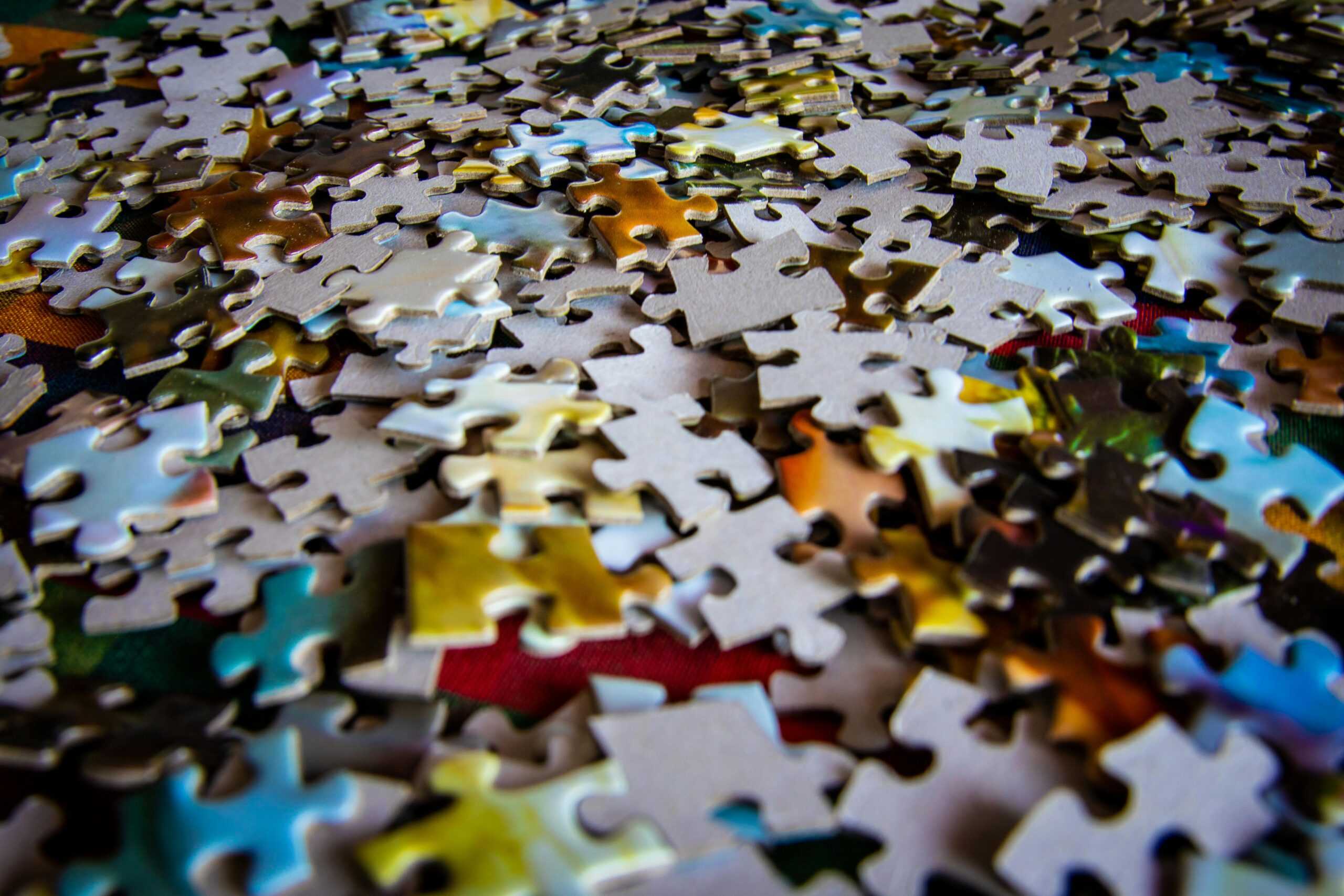 A colorful collection of jigsaw puzzle pieces scattered on a flat surface, ideal for hobby and leisure themes.