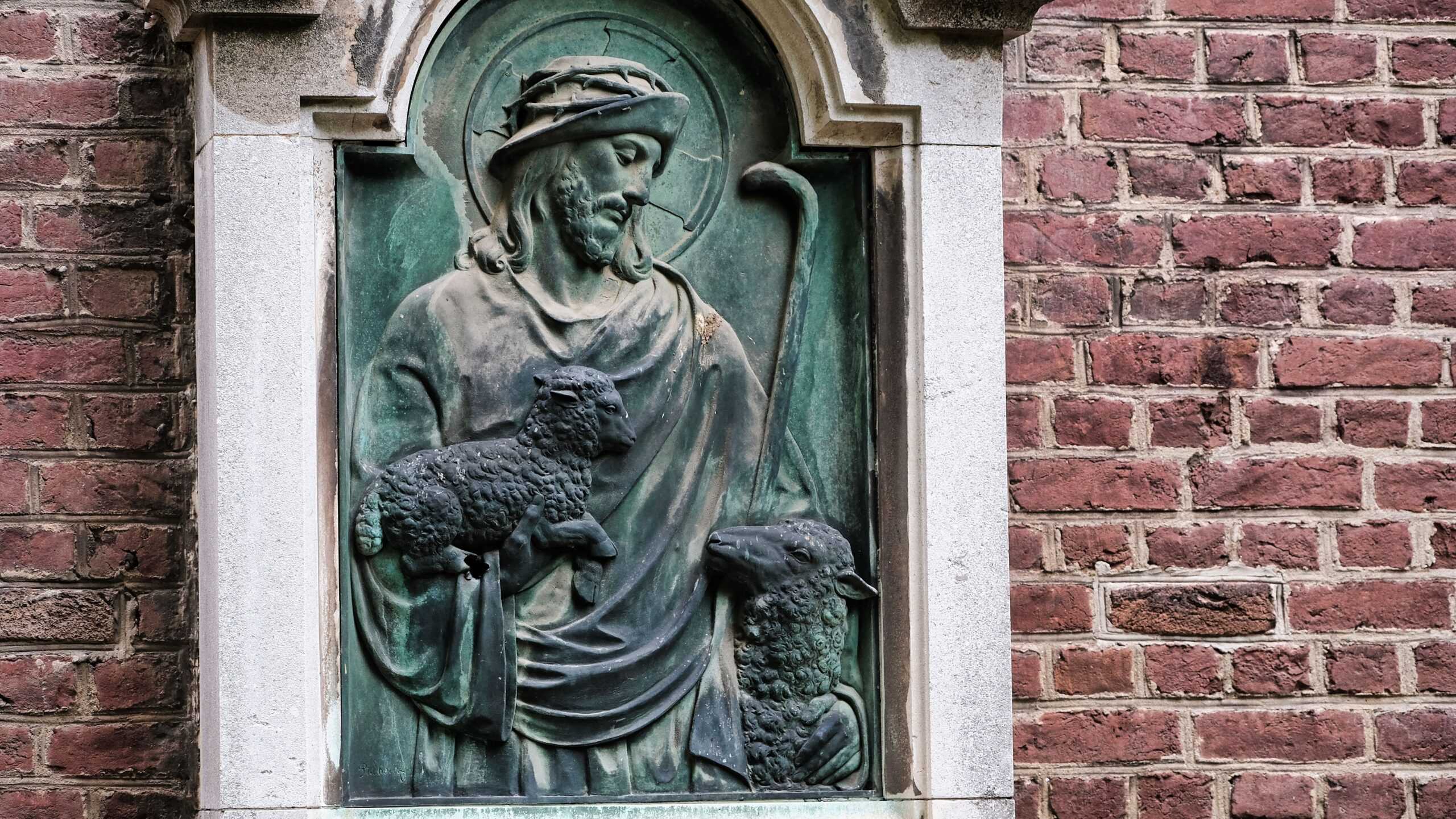 pexels photo 8472314 8472314 scaled Stone relief sculpture of a religious figure on a brick wall facade.