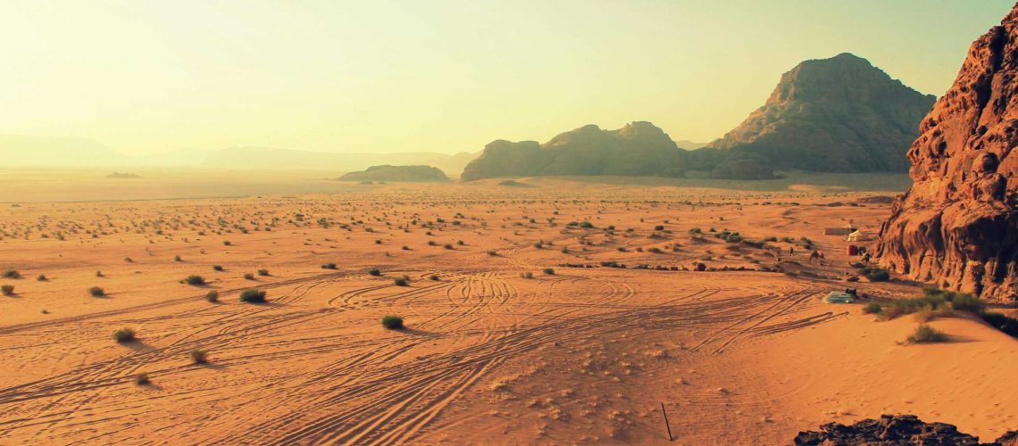 Explore the stunning beauty of Wadi Rum's arid desert landscape, bathed in warm sunset hues.