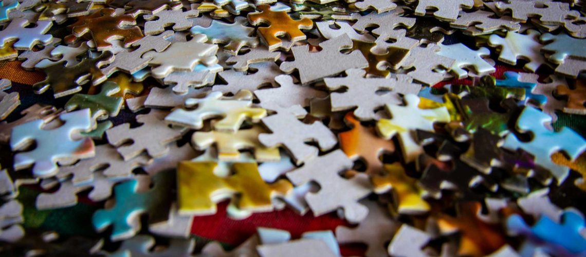 A colorful collection of jigsaw puzzle pieces scattered on a flat surface, ideal for hobby and leisure themes.