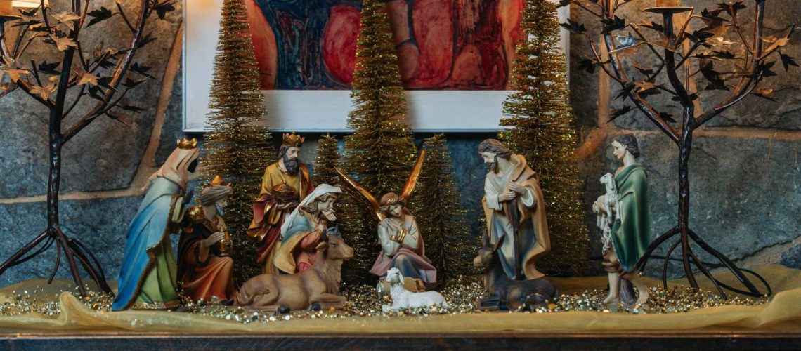 Festive Christmas nativity scene with figurines and warm lighting indoors creating a cozy holiday atmosphere.