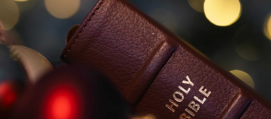 Close-up of a brown leather Holy Bible against a festive blurred lights backdrop.