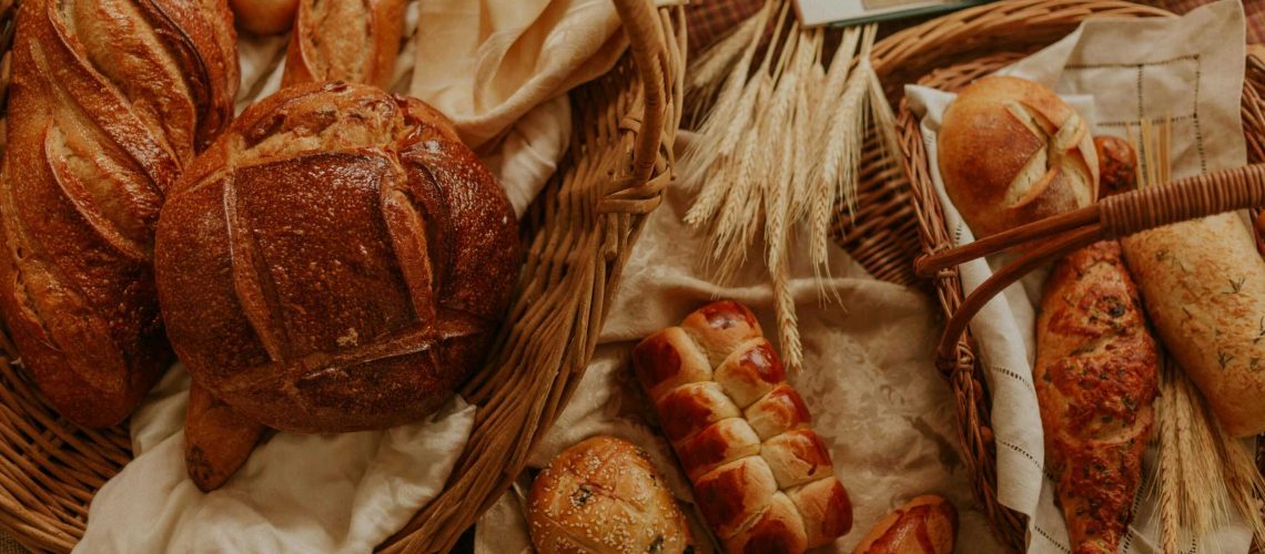 An assortment of artisanal bread displayed in wicker baskets, creating a rustic and warm atmosphere.