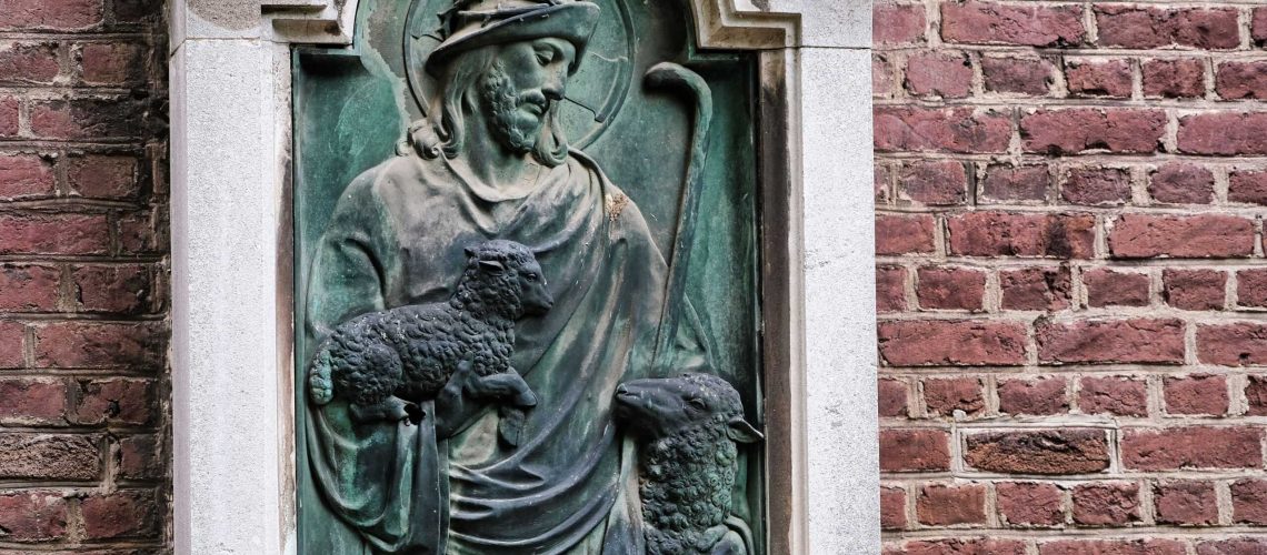 Stone relief sculpture of a religious figure on a brick wall facade.